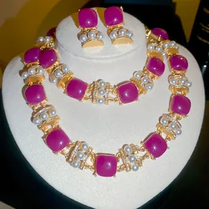 Close-up of vintage jewelry set showing purple resin stones and pearls on a white bust