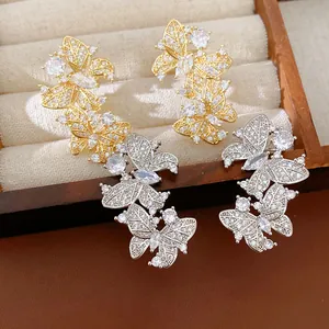 Dettaglio ravvicinato di orecchini a farfalla in oro 18k e argento con micro-pavé