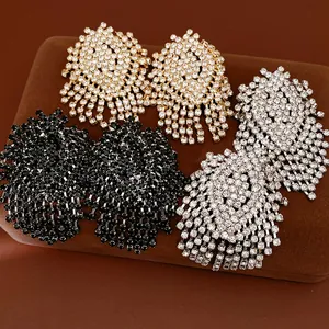 Close-up of sparkling geometric tassel earrings in gold, silver, and black rhinestone finish