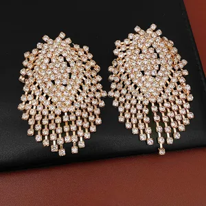 Detailed view of gold geometric tassel earrings with brilliant clear rhinestones.