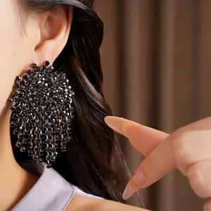 Close-up detail of black rhinestone tassel earrings with geometric silver needle stud
