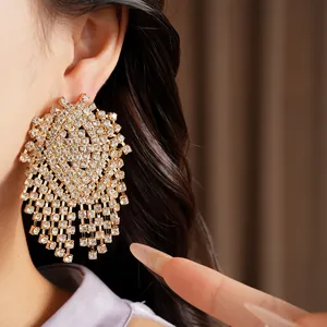 Macro view of luxurious sparkling crystal geometric tassel earrings worn by a model