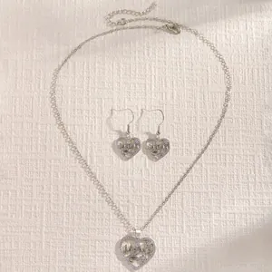 Detailed view of heart-shaped MaMa pendant and earrings set with zircon stones