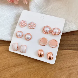 Primer plano de un elegante juego de pendientes de perlas y oro rosa en cartón blanco.