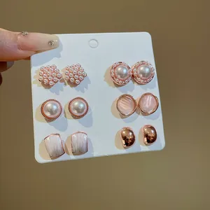 Vista detallada de un elegante juego de seis pares de aretes de perlas y oro rosa en una tarjeta