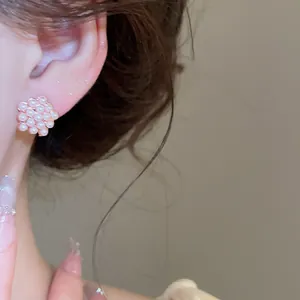 Primer plano detallado de pendientes de perlas en forma de flor en una modelo asiática