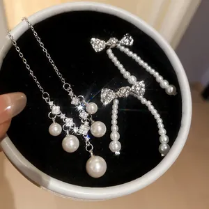 Elegant close-up of pearl necklace and bow earrings set in a circular jewelry box.