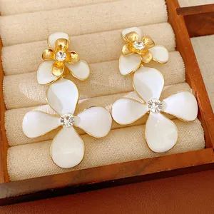 Primo piano di eleganti orecchini a fiore in smalto bianco con strass in un vassoio
