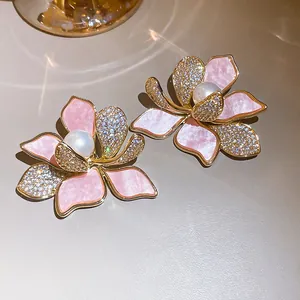 Nahaufnahme eleganter rosa Blumenohrringe mit Perle und Zirkon-Blütenblättern.