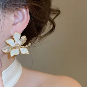 Detailansicht eines vergoldeten Blumen-Ohrsteckers mit Perlen und Zirkonia am Modell