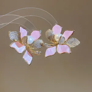 Makro-Detail von eleganten rosa Emaille-Blumenohrringen mit Perlen und Zirkon-Steinen