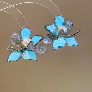 Detailansicht der eleganten blauen Blumenohrringe mit Perlen und Zirkonia.