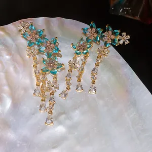 Primo piano di orecchini a nappa con fiori e zirconi colorati su una conchiglia