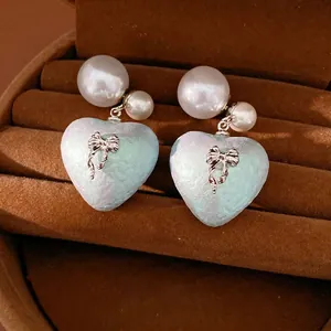 Eleganti orecchini a perno a cuore con fiocco e perle, finitura cangiante e ago in argento.