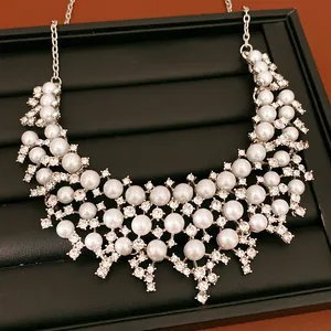 Gros plan d'un collier de perles vintage avec strass scintillants sur plateau noir