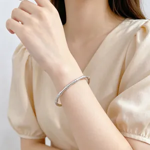Primer plano de un brazalete plateado minimalista con diseño de bambú en la muñeca