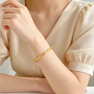Elegante primer plano de una pulsera minimalista de acero de titanio dorado con diseño de bambú.