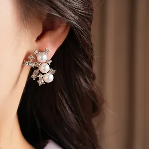 Élégantes boucles d'oreilles clous avec perles et strass brillants portées par un mannequin