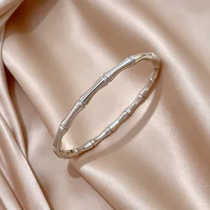 Detalle de primer plano de un brazalete de acero inoxidable con diseño de bambú plateado