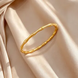 Primer plano de una elegante pulsera de acero de titanio dorado con diseño de bambú