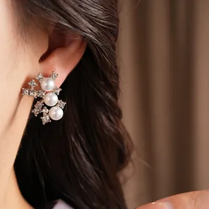 Détail de boucles d'oreilles élégantes en argent avec trois perles et strass