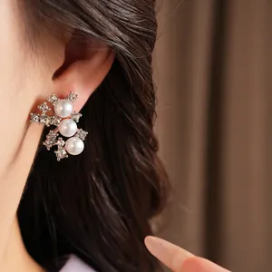 Vue détaillée de boucles d'oreilles argentées avec perles blanches et strass brillants