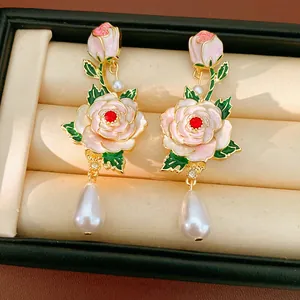 Macro view of vintage-style enamel flower earrings with elegant teardrop pearls.