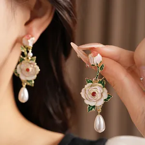 Detailed view of elegant enamel rose earrings with teardrop pearl and small red crystal