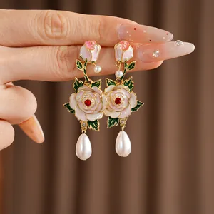 Detailed close-up of elegant enamel rose earrings with teardrop pearls and gold-tone finish