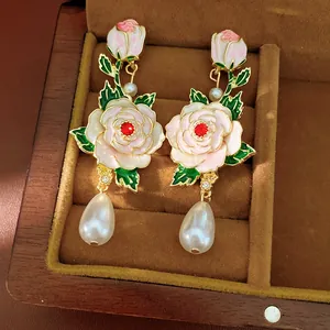 Detailed macro view of vintage enamel rose earrings with elegant teardrop pearl drops