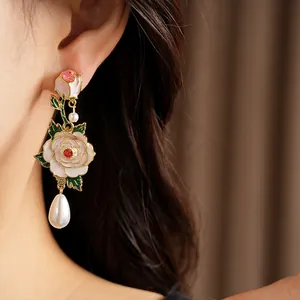 Close-up of exquisite enamel rose earrings featuring teardrop pearls and silver needle studs