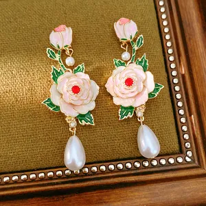 Detailed macro view of vintage style enamel rose earrings with elegant teardrop pearl accents