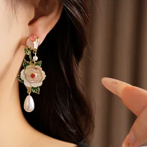 Close-up of exquisite enamel rose earrings featuring elegant pearl drops and red crystals