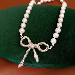 Elegante collana di perle con ciondolo a fiocco argento su supporto in velluto verde.