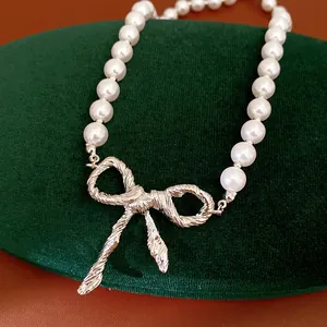 Primo piano di una collana di perle bianche con un ciondolo a fiocco d'argento operato