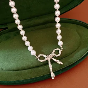 Primo piano di una collana di perle con ciondolo a fiocco d'argento in una scatola