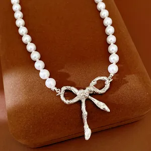 Dettaglio macro di un'elegante collana di perle con ciondolo a fiocco d'argento testurizzato.