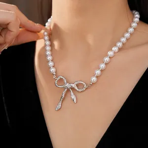 Dettaglio in primo piano di un'elegante collana di perle con fiocco d'argento.