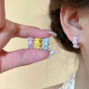 Close-up of colorful enamel floral hoop earrings in purple, yellow, and blue colors