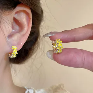 Close-up detail of dainty yellow enamel flower hoop earrings with crystal center for women