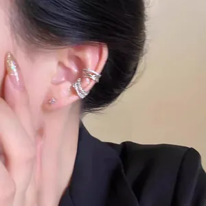 Macro view of a sparkling silver zircon criss-cross ear cuff worn on model's ear