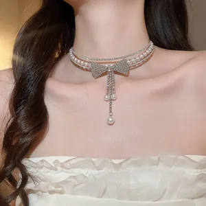 Detailed view of a multi-layer pearl choker with a sparkling rhinestone bow and tassels.