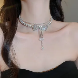 Close-up detail of a sparkly rhinestone bow choker necklace with elegant pearl tassels