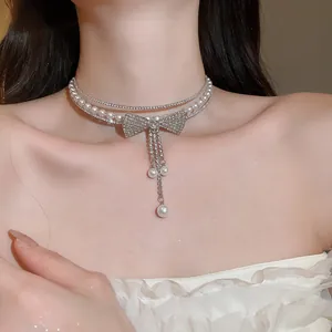 Close-up of sparkling rhinestone bow necklace with elegant white pearl tassels