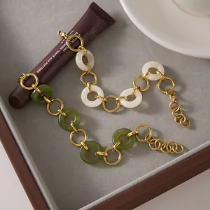 Close-up detail of stainless steel bracelets with green and white resin links on a tray