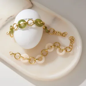 Detail shot of stainless steel bracelets with green and white resin rings on marble