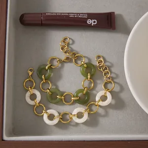 Detail shot of two gold stainless steel link bracelets with green and white resin rings.