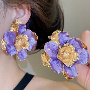 Dettaglio di orecchini a fiore viola con texture a pieghe dorata