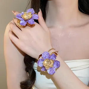 Dettaglio ravvicinato dell'anello a fiore viola e del bracciale rigido sul modello.