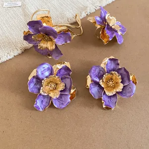 Vista dettagliata di un elegante set di gioielli fiori in smalto viola e oro lucido